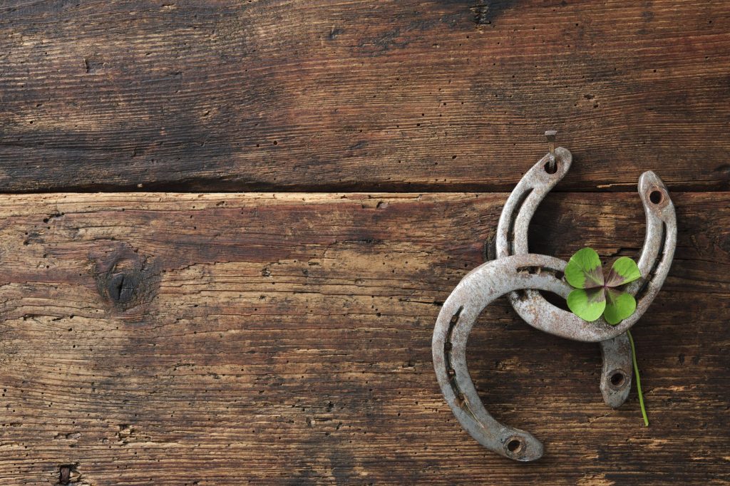 St. Patricks day, lucky charms. Two horseshoes with a four leaved clover on wooden board